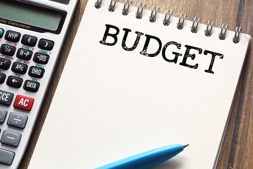 A calculator and blue pen lie next to a notepad with "BUDGET" in bold, meticulously outlining the Braces Payment Plan on a wooden surface in San Antonio, TX