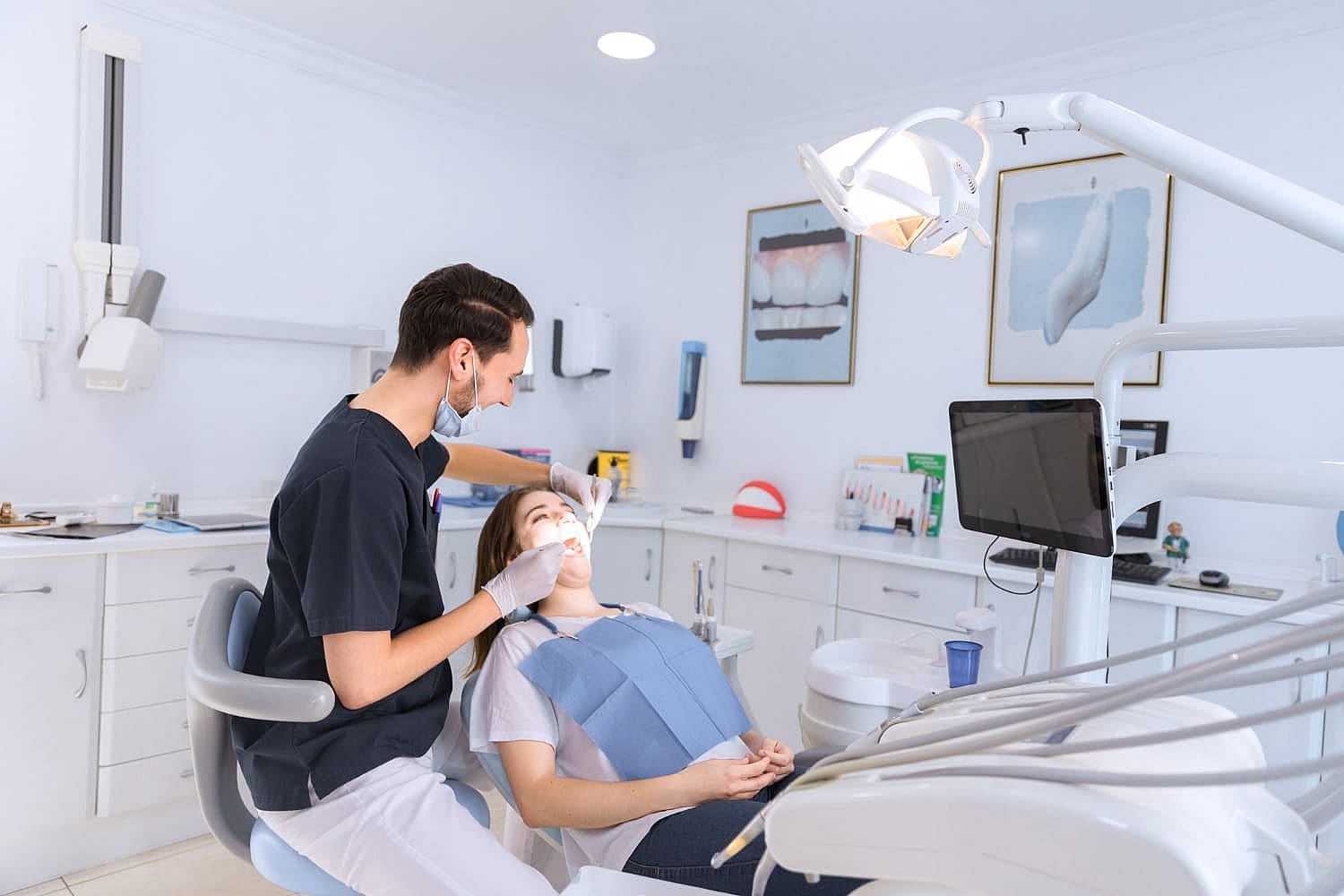 In a modern dental office, a dentist examines a patient while discussing the use of a palatal expander, with sleek equipment and tools visible around them in San Antonio, TX