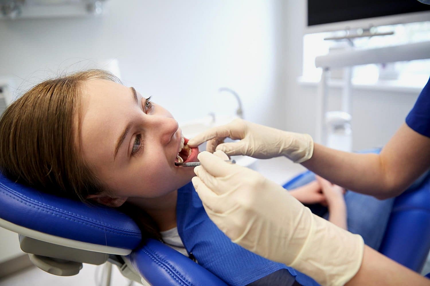 A woman with metal braces sits comfortably in a dentist chair, ready for her routine check-up in San Antonio, TX