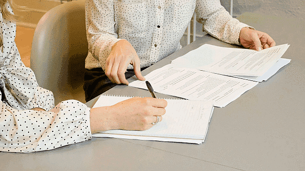 Two individuals in polka dot shirts work at a table, reviewing and writing on documents related to orthodontic insurance plans in San Antonio, TX