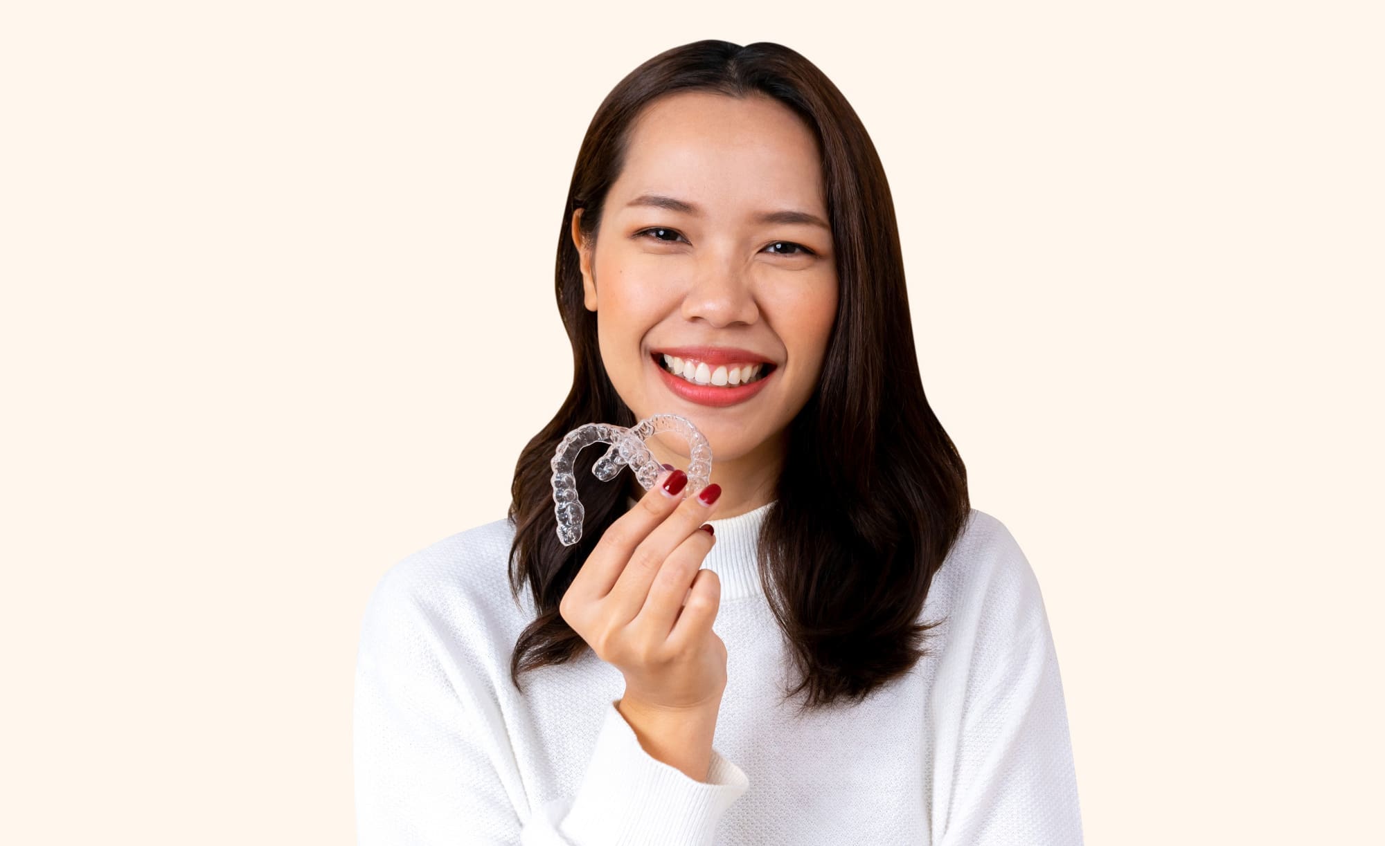 A woman with long dark hair smiles, holding Invisalign aligners for Fiesta Orthodontics in East San Antonio, TX.
