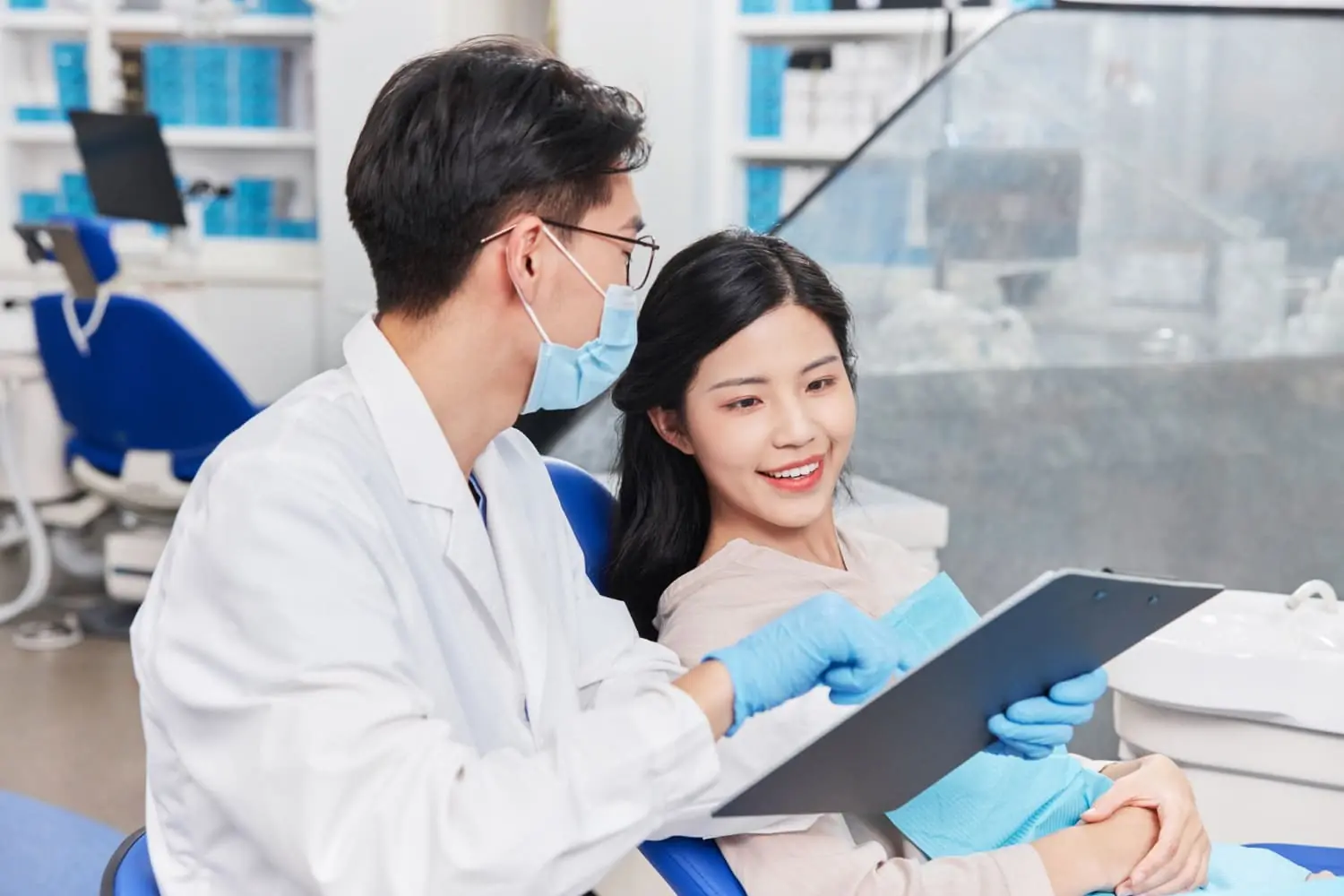 Dentists in white coats and discuss a patient in a dental office, planning the best approach for adult orthodontics in San Antonio, TX Dentists in white coats and discuss a patient in a dental office, planning the best approach for adult orthodontics in San Antonio, TX